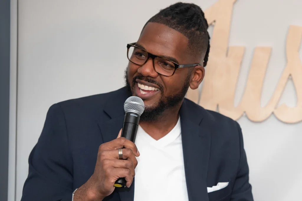 Brandon smiling and speaking into a microphone at the 2023 Just Start Summit